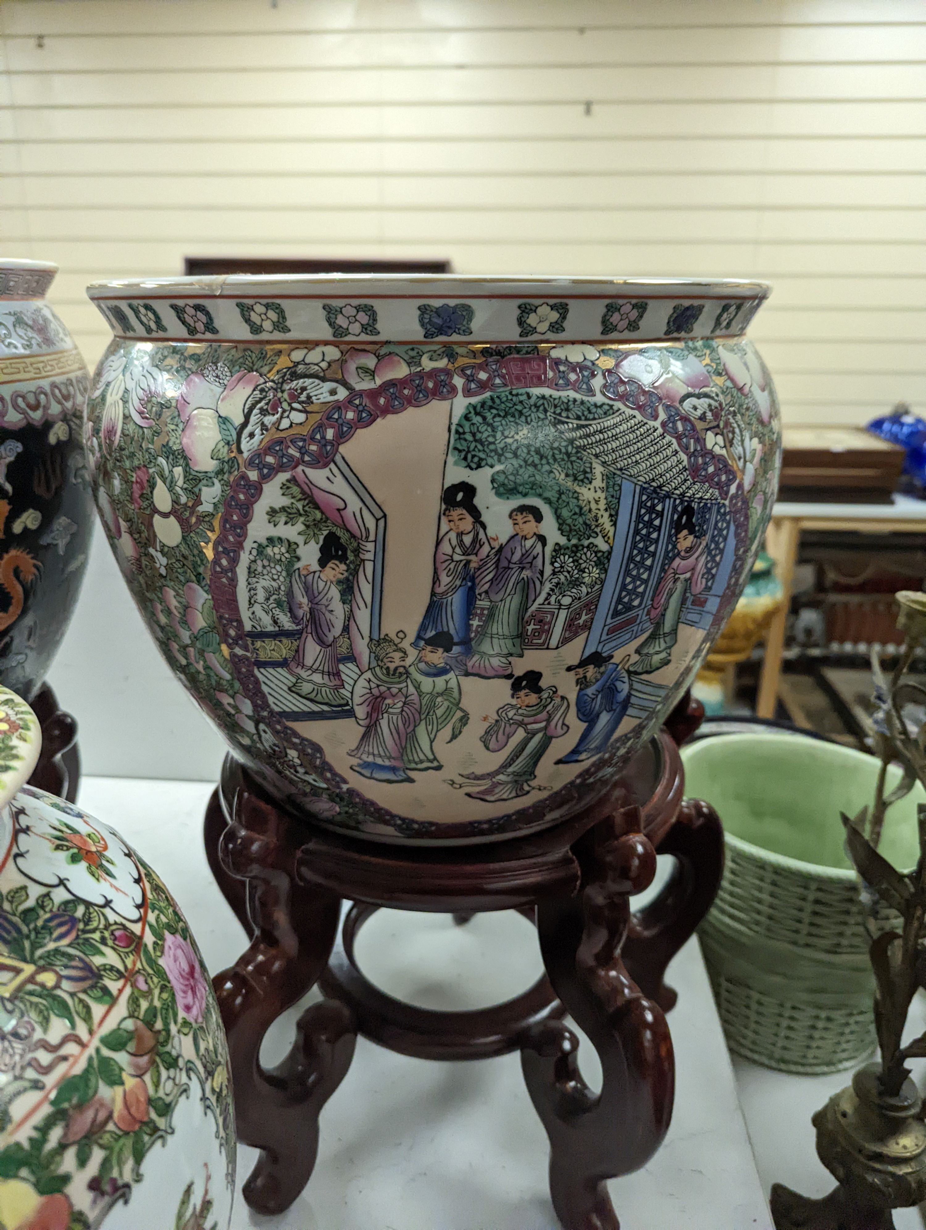 A pair of Chinese fish bowls on hardwood stands and a similar jar and cover, Fish bowls and stands 54 cms high.